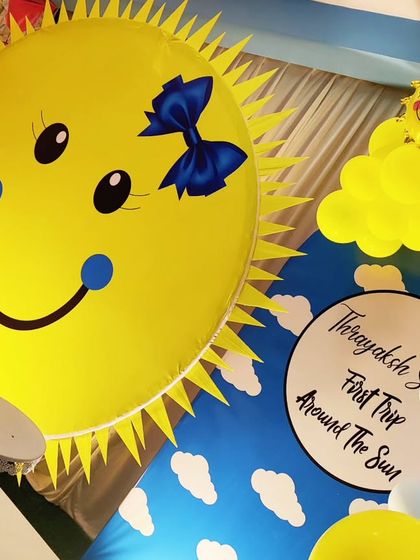 A close-up of a "First Trip Around the Sun" themed backdrop, featuring a giant smiling sun.