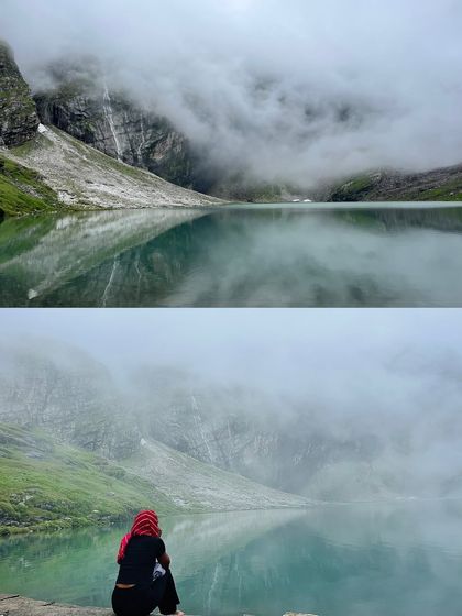 A trekker sitting by the serene, glacial lake of Hemkund Sahib, surrounded by mist and mountains. It's a place for quiet contemplation and feeling a divine energy.