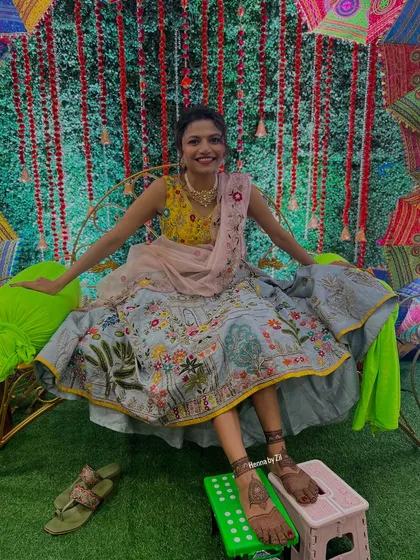 A joyful bride showing off her full lehenga and her beautiful foot mehendi.
