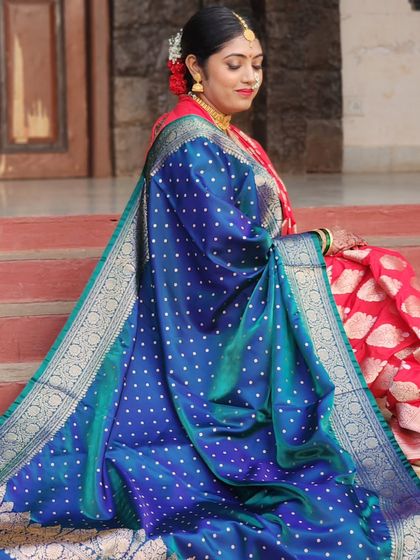 A regal shot showcasing the beautiful drape of the bride's blue and red Paithani shawl. The entire look is a celebration of color and tradition.