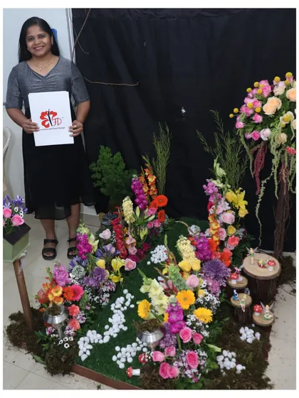 The culmination of months of learning. A graduating student presents her final project, a magical garden scene filled with a colorful profusion of flowers, showcasing her advanced design skills.