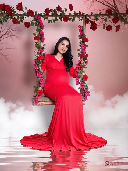 A creative studio portrait on a floral swing with a pink sky backdrop and a water reflection, creating a fantasy-like atmosphere.