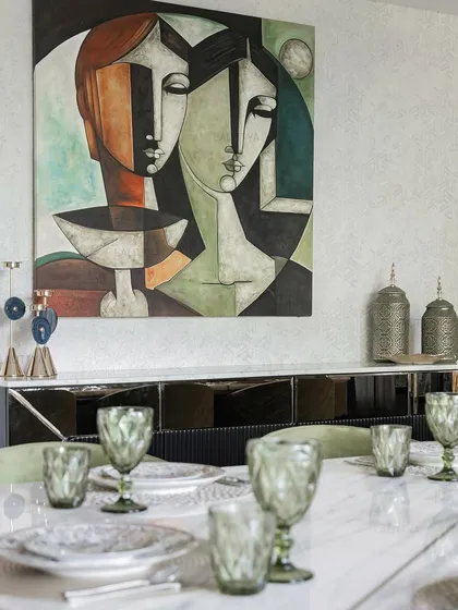 Touches of green, gold, and glass make this dining setting one to linger in. The table is set with green glassware that echoes the color of the chairs and the chandelier above.