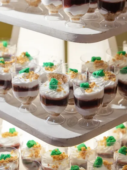 Tiramisu-style dessert cups, layered with cream and coffee-soaked sponge, and topped with a sprinkle of green crumble.