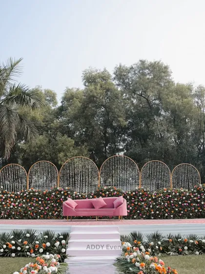 A wide view of the pink floral stage, showing the full scale of the design with a lush floral aisle leading up to it, perfect for a day event.