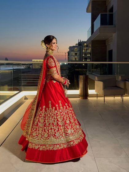 A full-length shot of the bride in her red lehenga, her white rose bun providing a beautiful contrast against the sunset.