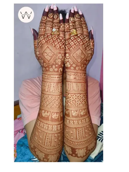A bride proudly displays her full engagement henna, covering her hands and arms in beautiful, intricate patterns.