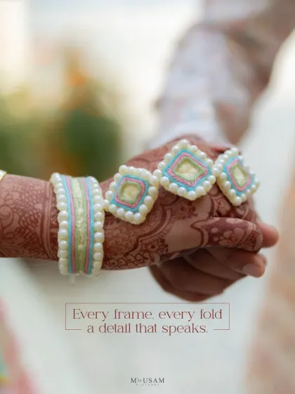 A close-up of a bride's hand with unique, pastel-colored floral jewelry. This shot highlights the modern and personalized details that brides are choosing for their pre-wedding functions.