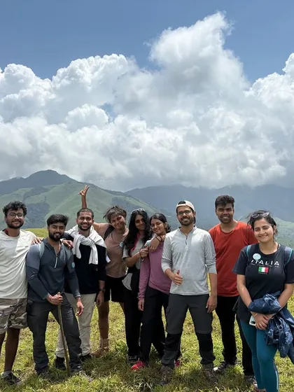 On a bright, sunny day, this group celebrates reaching a scenic viewpoint. The shared joy and stunning backdrop make for a perfect memory.
