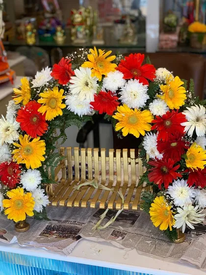 A beautiful floral arch made of colorful gerbera daisies, designed to be placed around a small idol or on a tabletop for festive home decor.