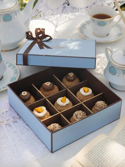Explore our delicate and fluffy Choux Pastries, presented in a beautiful nine-piece gift box. This assortment shows a variety of our flavours, including Chocolate Hazelnut, Mango & Cream Cheese, and Biscoff, each piped with a creamy filling and a distinct topping.