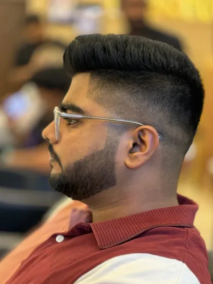 A sharp men's haircut focusing on the details. This style features a clean skin fade that blends seamlessly into a voluminous, textured top, paired with a perfectly lined-up beard.