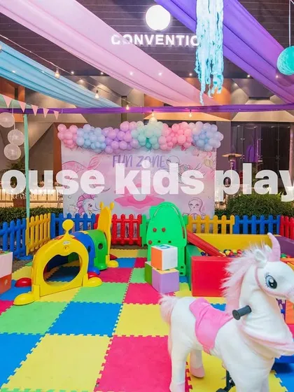 Another angle of the indoor rainbow play area, showing the plush unicorn rocker and climbing structures that encourage active play.