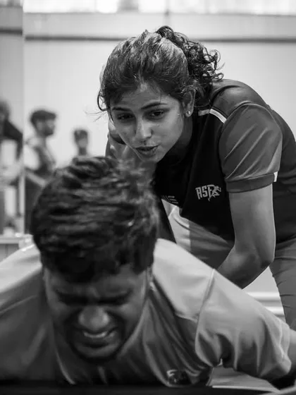 A coach works with an athlete on the floor, demonstrating the supportive and hands-on nature of our community. This black-and-white shot captures a moment of intense focus and trust.