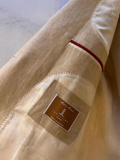 The inside of our beige linen blazer, showing the clean finishing and partial lining. This construction makes the jacket lightweight and perfect for summer.