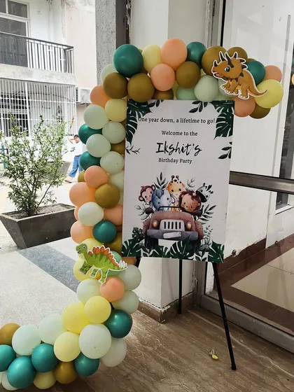 A simple yet charming welcome setup for Ikshit's jungle-themed birthday, with a custom sign and a balloon garland featuring cute dinosaur accents.
