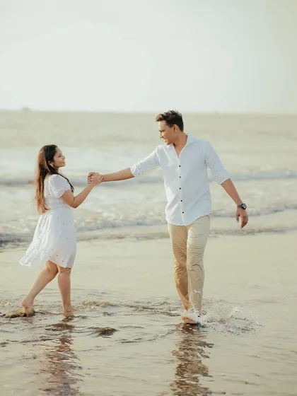 Leading each other into a new chapter. A beautiful, dynamic shot of a couple enjoying their pre-wedding photoshoot on the beach, filled with movement and joy.