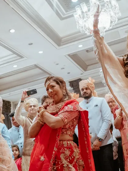 The bride's mother and sisters dancing with joy as they welcome the groom. We ensure the families are as much a part of the celebration as the couple.