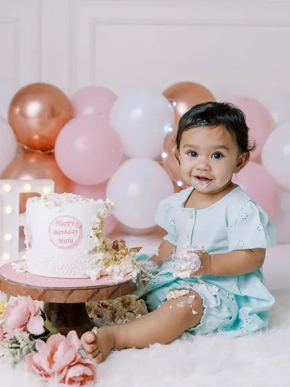 A sweet smile and a little bit of cake on her face. This is the perfect portrait from a first birthday cake smash, full of innocence and fun.