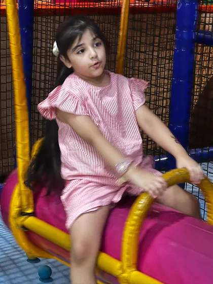 A girl enjoys a ride on the swinging log, a fun feature that tests balance and coordination.