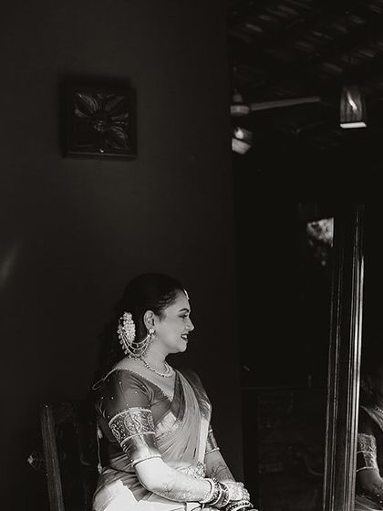 A black and white portrait of a bride, her reflection in the mirror adding depth to the image.