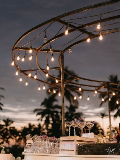 The bar at the Goa event, with hanging Edison bulbs creating a warm and festive glow against the night sky.