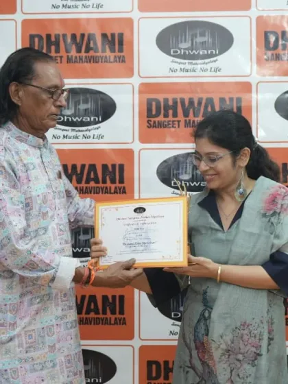 A senior guru presents a certificate to an adult student, honoring her dedication.