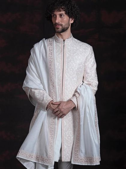 This sherwani, with its delicate all-over embroidery and accompanying stole, is crafted for a groom seeking understated grace. The light fabric and fine threadwork make it a sophisticated choice for daytime or destination weddings.