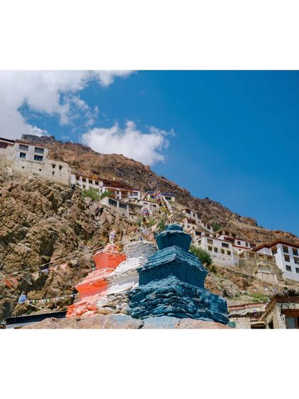 A low-angle view of the Karsha Monastery, showing its position built up the side of a rocky mountain.