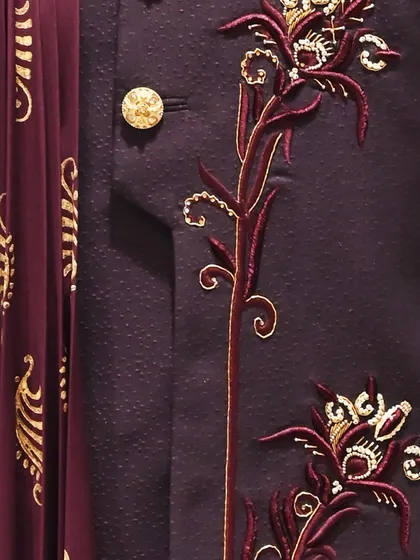 A detailed close-up of the floral embroidery on the wine-colored sherwani, highlighting the texture and artistry.