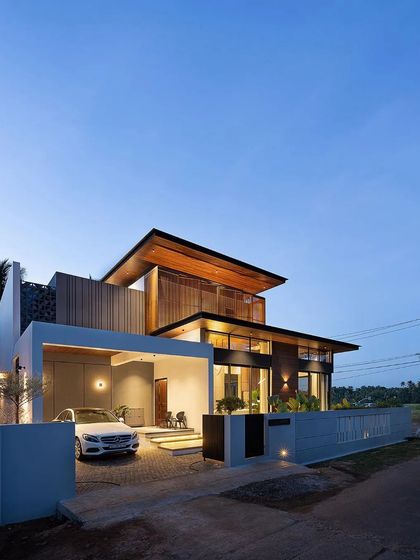 The 'Open Sky Residence' at dusk, when the architectural lighting highlights its strong geometric lines and warm wooden elements.