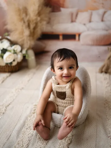 A comfy and cute portrait of a baby sitting in a soft chair. These sessions are designed to be relaxed and capture your baby's natural charm.