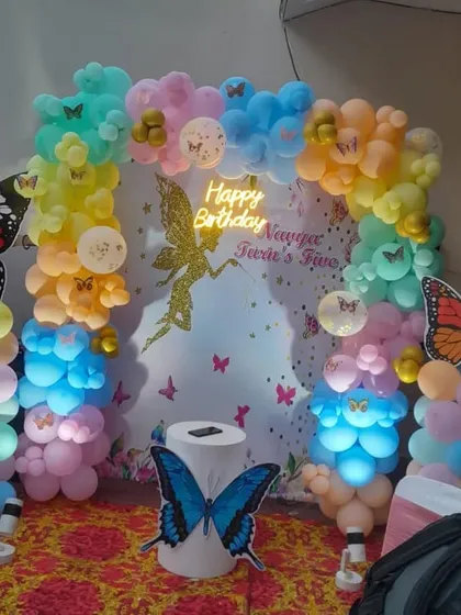 A fairy and butterfly themed birthday party with a custom backdrop and colorful, illuminated balloon clouds.