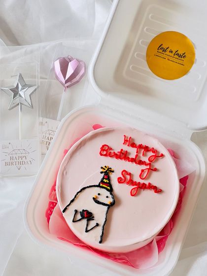 A cute and simple character design for a birthday. This pink bento cake features a cartoon figure in a party hat, ready to celebrate.