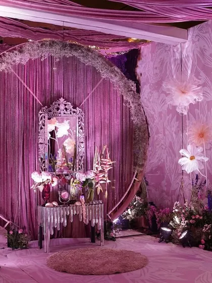 This fairytale photo booth was a dream to create. A large circular frame was set against pink bead strings and adorned with moss, feather blooms, and oversized floating flowers for a touch of whimsy.