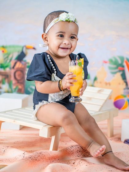 Enjoying a glass of juice on a sunny day. The bright colors and happy smile make this beach-themed photo feel warm and cheerful.