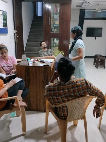 A group of actors seated around a table for a script reading session. This is a fundamental part of our process to understand the play's structure and themes.