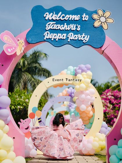A whimsical entrance arch for "Taashvi's Peppa Party," with the birthday girl posing in the center.
