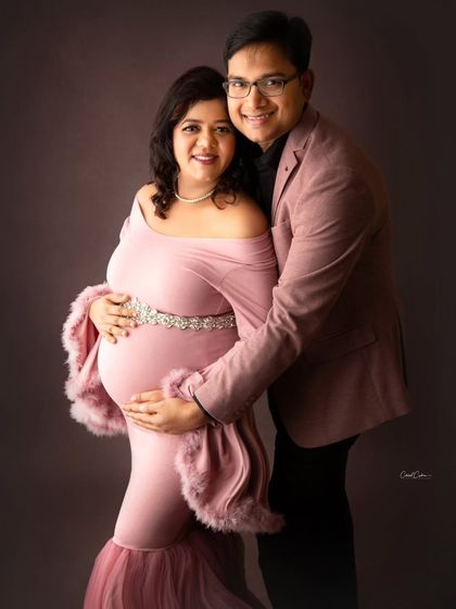 A sweet and coordinated couple's portrait. The parents-to-be are dressed in matching shades of pink, looking absolutely adorable together.