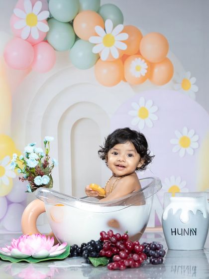 A happy baby enjoying a milk bath with oranges and grapes.