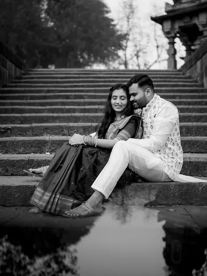 A serene and artistic pre-wedding portrait. The reflection in the water and the historic setting are enhanced by the dramatic contrast of black and white.