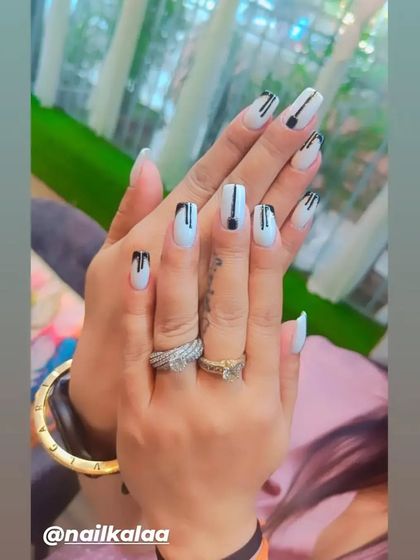 A chic and modern design with a white base and black "drip" effect art on square-shaped nails.