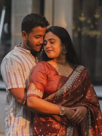 A warm, golden-hour portrait. The setting sun casts a beautiful light on the couple, creating a soft and romantic mood.