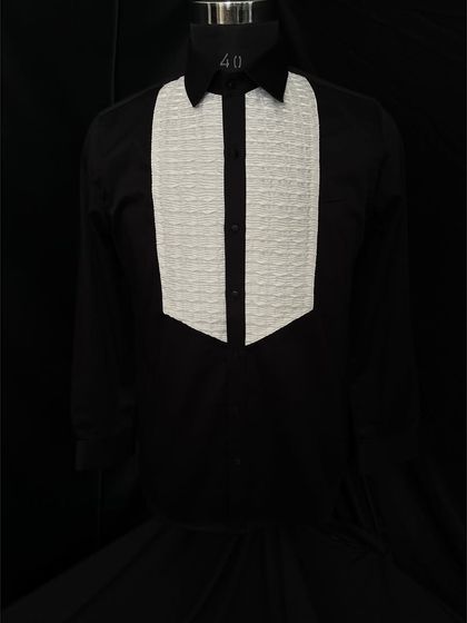 A reverse on the classic, this black tuxedo shirt features a contrasting white textured bib. It's a daring and stylish choice that pairs exceptionally well with both black and colored tuxedo jackets.