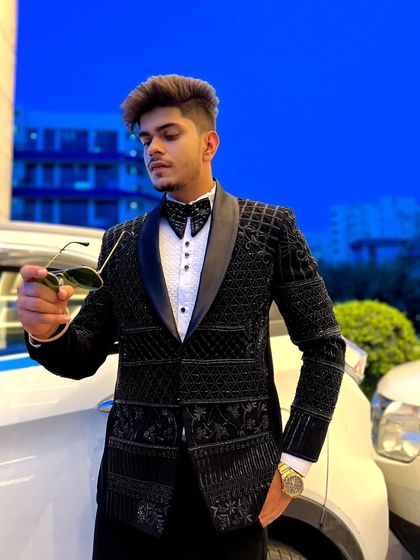 A close-up of the black beaded tuxedo, highlighting the detailed craftsmanship and the luxurious texture of the jacket.