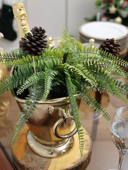 Our golden champagne bucket, repurposed here as a festive planter with ferns and pinecones. This shows the versatility of our pieces, perfect for adding a creative touch to your holiday decor.