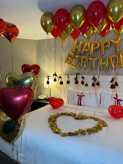 A close-up of the bed, showing the hanging roses from the balloons and the petal heart.