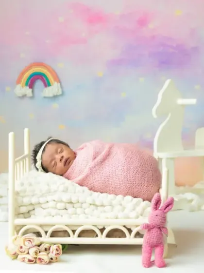 A dreamy newborn portrait with a pastel rainbow backdrop, creating a soft and magical atmosphere for your baby's first photos.