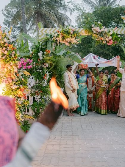 A family member performs a traditional welcoming ritual with a lamp as the couple makes their entrance.