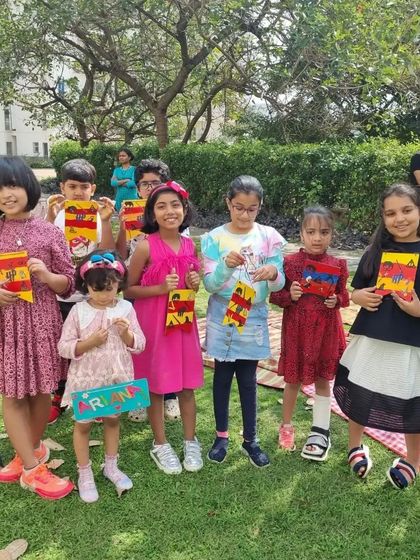 A group of kids proudly holding their finished art projects at an outdoor birthday party.